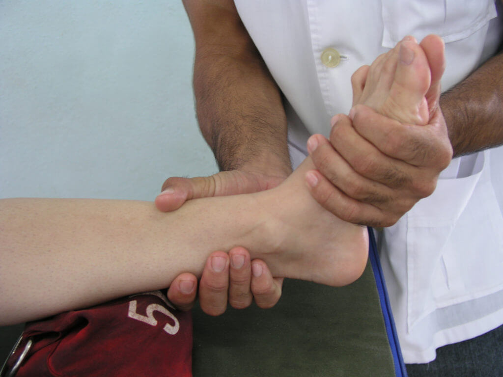 Close up photograph of a physical therapist gripping a patient's foot for treatment.
