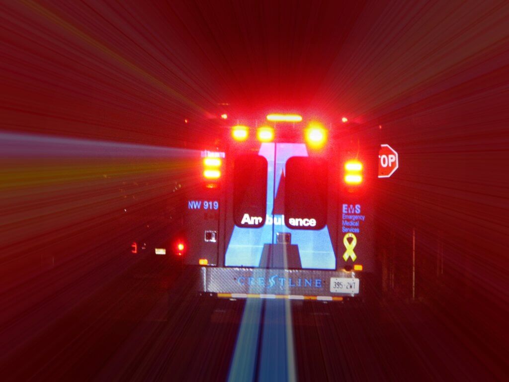 Photograph of an ambulance driving through a tunnel with lights and sirens on.