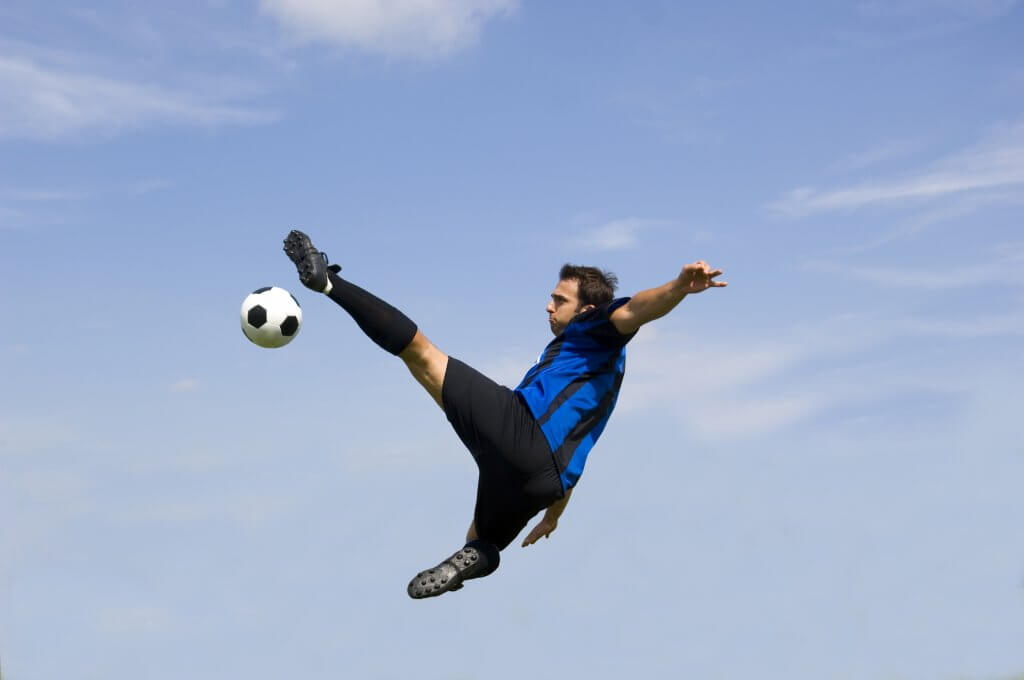 Man leaping through the air to kick a soccer ball